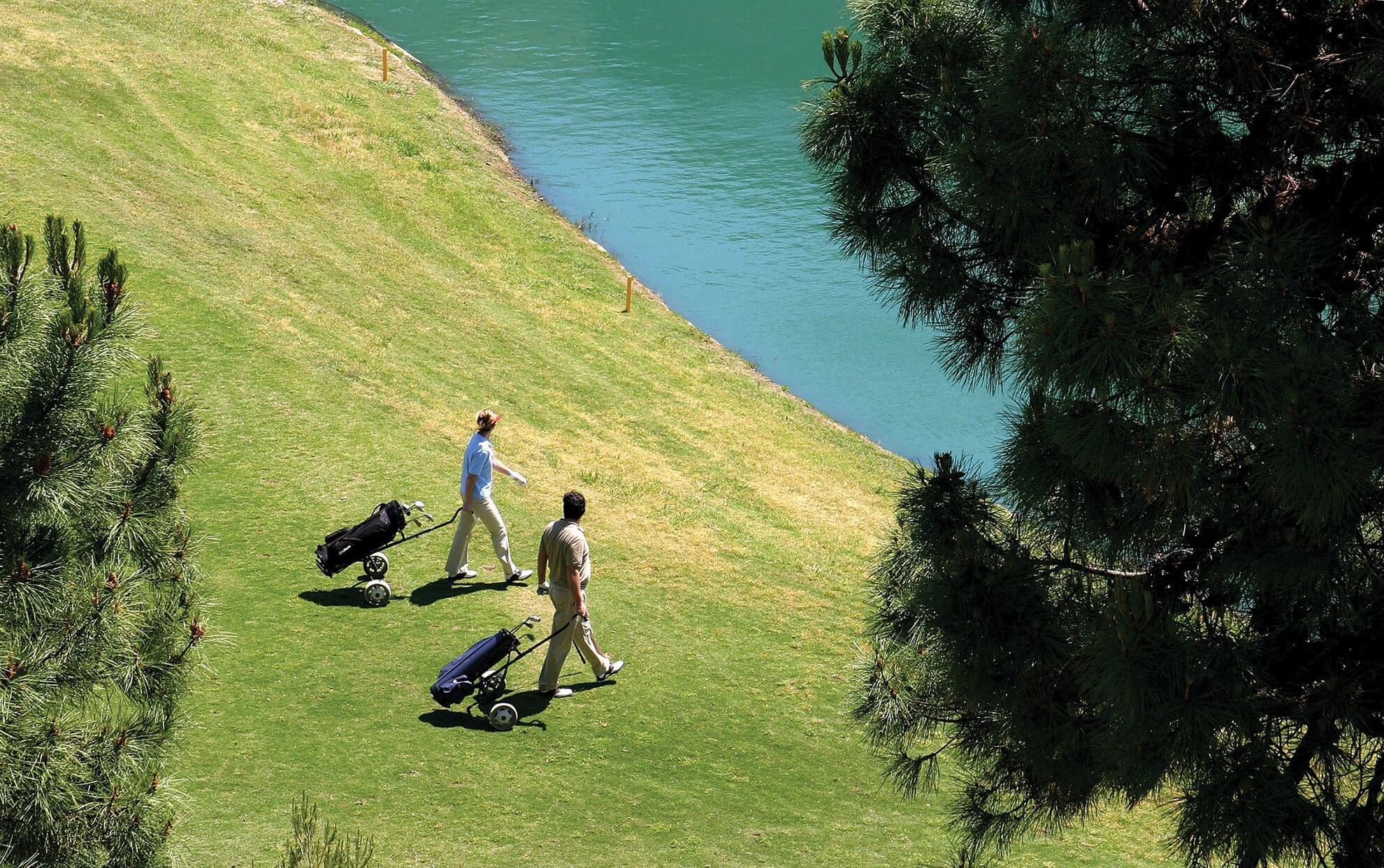 Two men going around a golf course nearby a lake