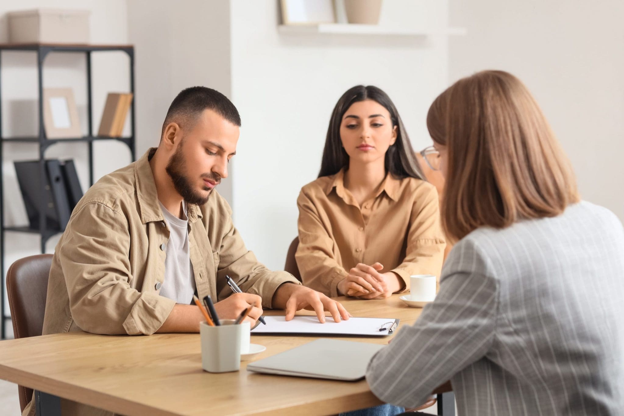 Separating couple seated with a professional mediator in a calm office setting, discussing parenting and financial arrangements through family mediation.