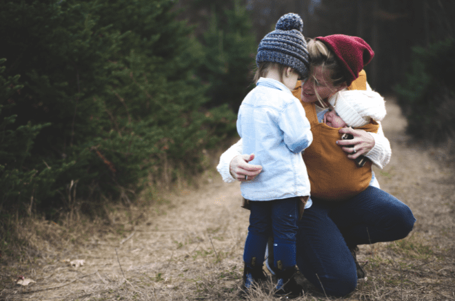 a woman hugs her toddler with one arm as she holds her other baby. EOTAS package