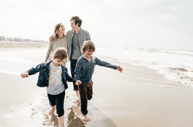 a family walking along the beach smiling,